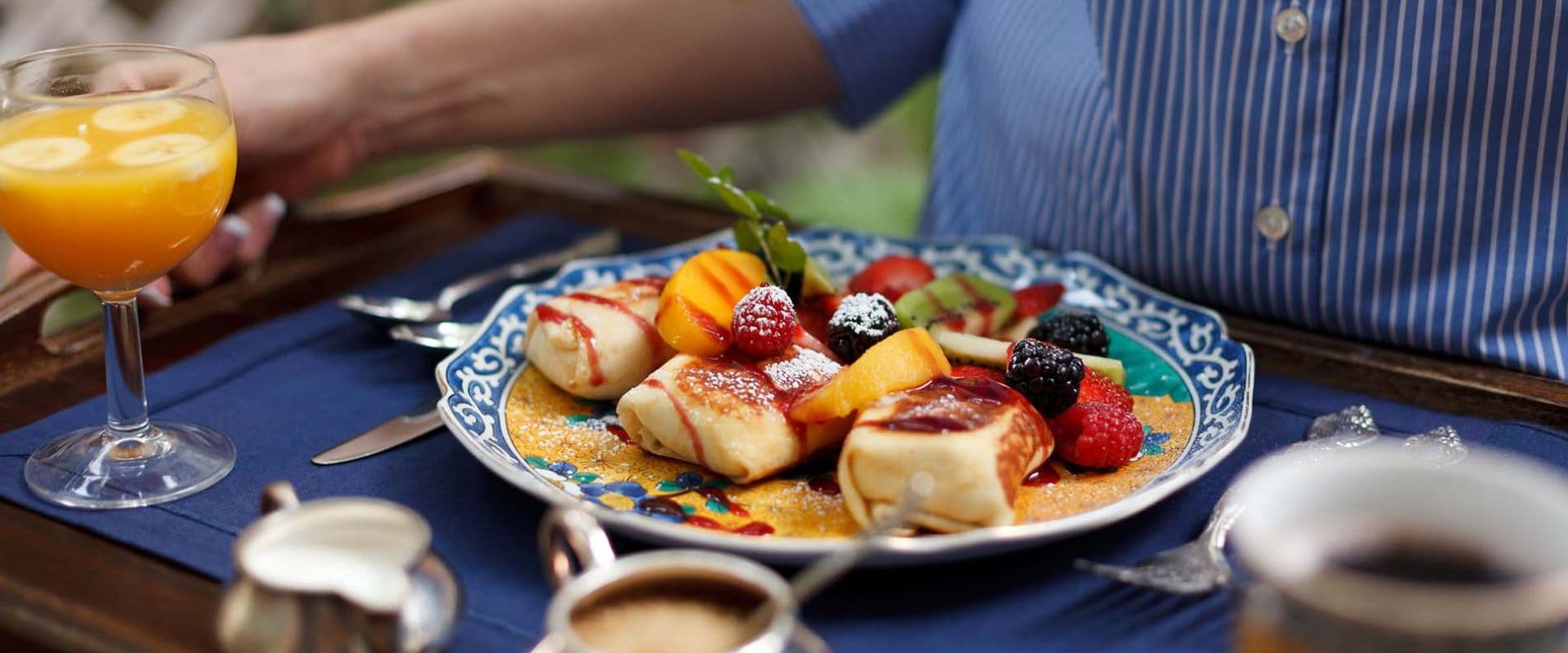 A breakfast plate with pancakes and fresh fruit, accompanied by a glass of orange juice.