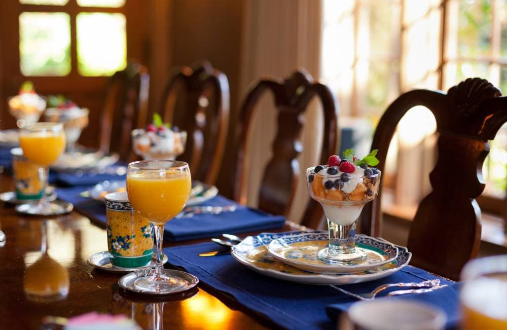 A beautifully set dining table featuring parfaits and orange juice in elegant glassware.