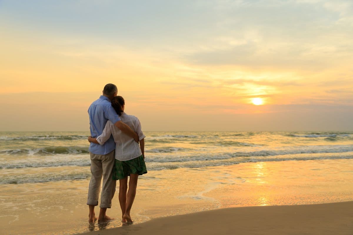 A couple embraces on the beach at sunset.