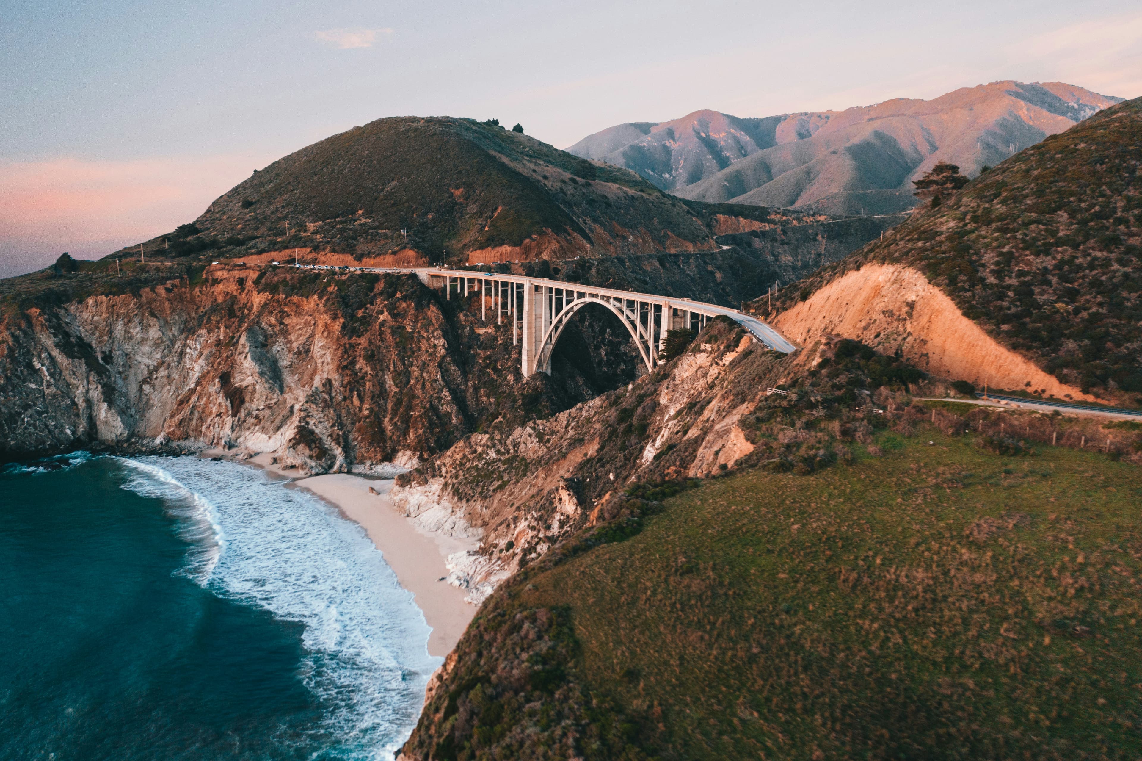 A dramatic coastal scene featuring a bridge spanning a rocky cliffside near the ocean.